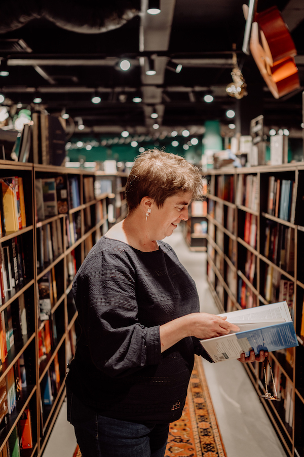 Photo of Rachel Amies holding a book open in a bookshop. Photo is the main image of Crazy Digital Creative's Tone of Voice copywriter service page.